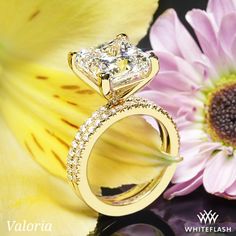 a diamond ring sitting on top of a yellow flower next to a pink and white flower