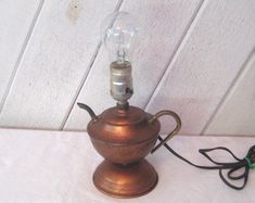 an old fashioned teapot lamp with a glass bulb on it's top, sitting on a table