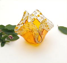 a glass vase sitting on top of a table next to a green leafy plant