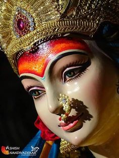 a close up of a person wearing a mask and headdress with jewels on it