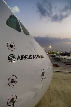 an airplane is parked on the tarmac at dusk with other planes in the background