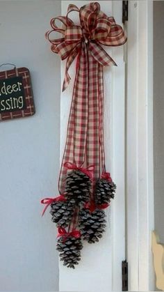 two pine cones tied to a door hanger with a red and white checkered bow