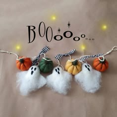 three halloween decorations are hanging from a string on a brown background with the words boooo written above them