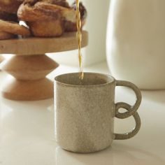 coffee being poured into a cup with doughnuts in the background