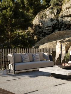 an outdoor seating area with two couches and a fire pit in front of some rocks