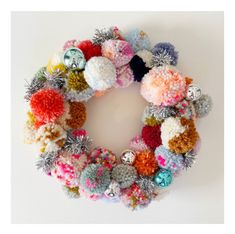 a multicolored knitted christmas wreath hanging on a wall with ornaments around it