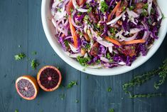 a white bowl filled with coleslaw next to sliced blood oranges