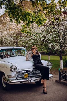 a woman sitting on the hood of an old car