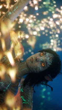 a woman is floating in the water with her eyes wide open and glowing lights all over her body