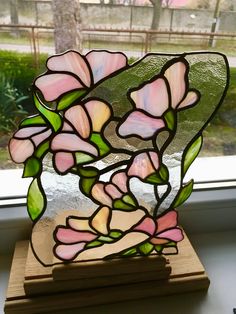 a stained glass vase sitting on top of a wooden stand in front of a window