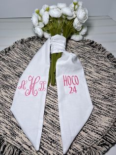 two white towels with pink monogrammed font on them sitting on top of a table