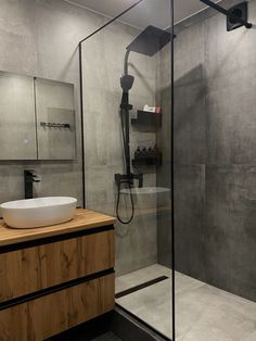 a bathroom with a glass shower stall and wooden countertop, along with a white bowl sink