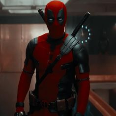 a deadpool character standing in a room with lights on and holding two knives up to his chest