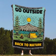 a person holding up a sign that says go outside back to nature with a tent in the background