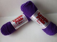 two skeins of purple yarn sitting next to each other on a white surface