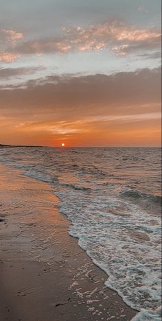 the sun is setting over the ocean with waves coming in to shore and people walking on the beach