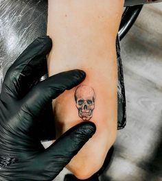 a person with black gloves on their feet has a skull tattoo