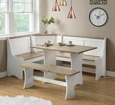 a kitchen table with benches and a clock on the wall above it, in front of a window