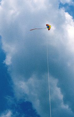 a kite flying high in the sky on a cloudy day with blue skies and white clouds