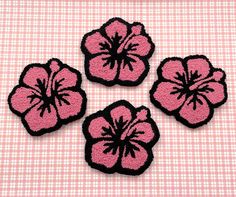 three pink and black flowers sitting on top of a checkered tablecloth covered surface