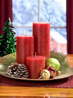 three red candles sitting on top of a plate next to christmas decorations and pine cones