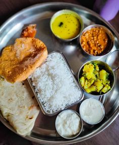 a silver plate topped with rice and different types of sauces on top of it