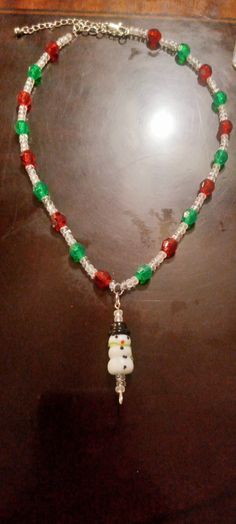 a beaded necklace with an owl and snowman charm hanging from it's side