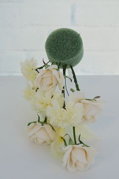 white flowers are arranged in front of a green hat on top of the headpiece