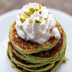 a stack of pancakes topped with whipped cream and pistachio