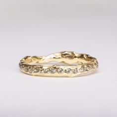 a gold wedding band with small diamonds on it's sides, set against a white background