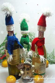 three bottles of wine with knitted hats on them and lemons in the foreground