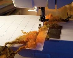 the machine is cutting fabric on the sewing machine's edge with orange colored yarn