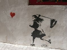 a stencil on the side of a building depicts a woman holding a flag