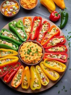 colorful peppers arranged in a circle on a plate with dips and condiments