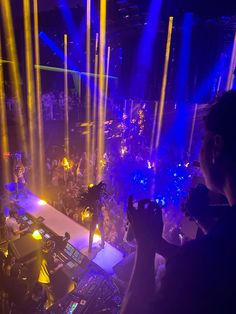 a concert scene with people on stage and bright colored lights shining down the center of the room