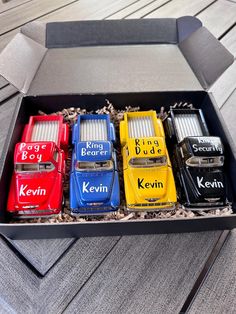 a box filled with different colored cars on top of a wooden floor next to a wall