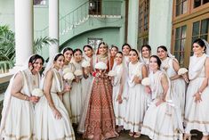 a group of women standing next to each other in front of a green building with white flowers