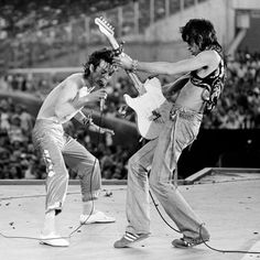 the rolling stones performing on stage in front of an audience with their guitars and microphones