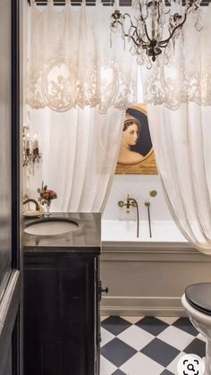 a bathroom with black and white checkered flooring, a chandelier and a painting on the wall