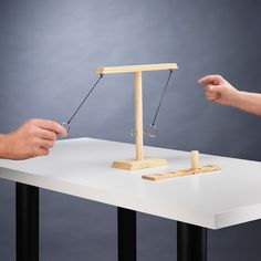 two hands are trying to pull the balance beam from one another on a table top