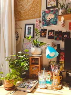 a cluttered desk with plants and pictures on the wall