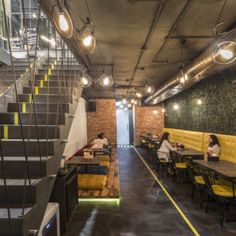 the interior of a restaurant with yellow booths and stairs leading up to the second floor