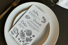 a white plate topped with a menu next to a fork and knife on top of a table