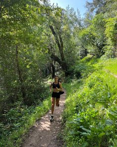 a woman running down a trail in the woods