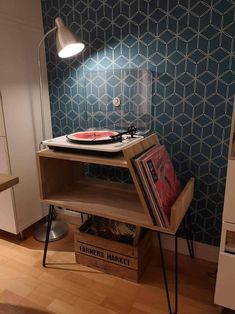 a record player is sitting on top of a wooden shelf in front of a blue wall