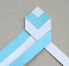 an origami cross made out of blue and white paper on a gray surface