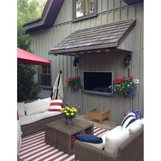 an outdoor living area with couches, tables and umbrellas on the side of a house