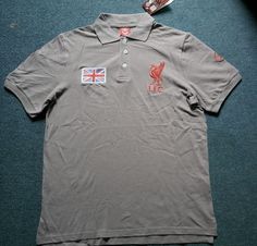 a grey polo shirt with the flag of england on it and two small stickers