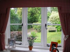 an open window with a bench in the back ground and flowers on the windowsill