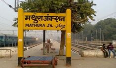 there is a yellow sign that says mumbai on it and people sitting at the train station